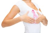 A woman with pink breast cancer awareness ribbon checking breast