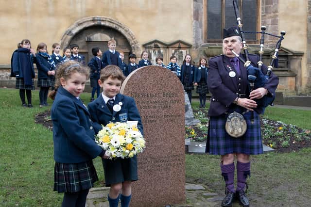 Piper Jennifer Hutcheon plays as George Heriot's pupils Arthur Rudd and Imogen Piper, both seven, lay flowers at the Greyfriars Bobby's grave. PIC: Alan Simpson Photography.