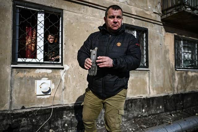 A man holds the remains of a mortar which exploded in front of a building in the town of Schastia, near the eastern Ukraine city of Lugansk, on February 22, 2022, a day after Russia recognised east Ukraine's separatist republics and ordered the Russian army to send troops there as "peacekeepers."