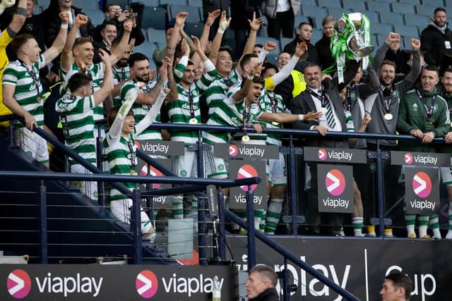 Surrounded by his players, Celtic manager Ange Postecoglou lifts the League Cup after the win over Rangers.