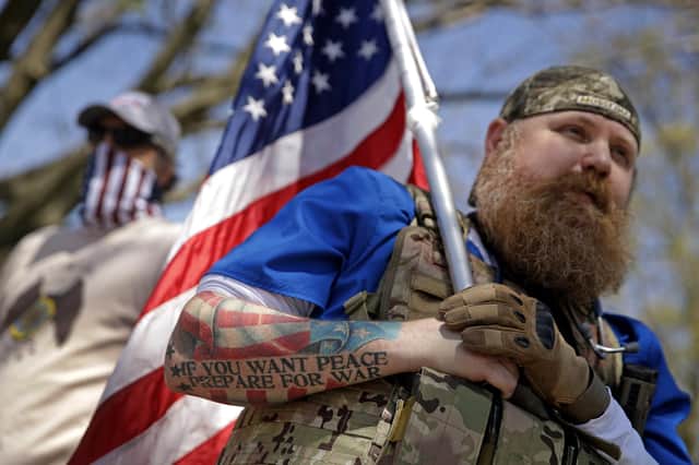 Wesley Ralston, from Dodge City, Kansas, stands with the flag and his guns in front of the Statehouse during a rally against stay-at-home orders put into place due to the Covid-19 coronavirus pandemic (Picture: Charlie Riedel/AP)