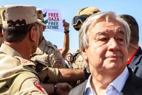 Protesters raise signs in solidarity with Palestinians in the Gaza Strip as Egyptian army officers and bodyguards escort United Nations Secretary-General Antonio Guterres to his vehicle (Image: KEROLOS SALAH/AFP via Getty Images)