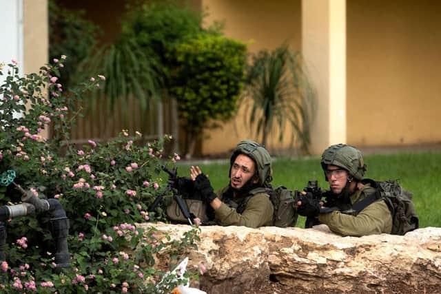 Israeli soldiers take cover as they are search for Hamas militants on the street of Sderot .