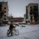 A man pushes his bike on a snow-covered street next to destroyed residential buildings in Borodyanka, near Kyiv, earlier this month (Picture: Dimitar Dilkoff/AFP via Getty Images)
