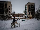 A man pushes his bike on a snow-covered street next to destroyed residential buildings in Borodyanka, near Kyiv, earlier this month (Picture: Dimitar Dilkoff/AFP via Getty Images)