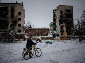 A man pushes his bike on a snow-covered street next to destroyed residential buildings in Borodyanka, near Kyiv, earlier this month (Picture: Dimitar Dilkoff/AFP via Getty Images)