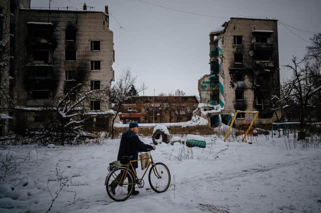 A man pushes his bike on a snow-covered street next to destroyed residential buildings in Borodyanka, near Kyiv, earlier this month (Picture: Dimitar Dilkoff/AFP via Getty Images)
