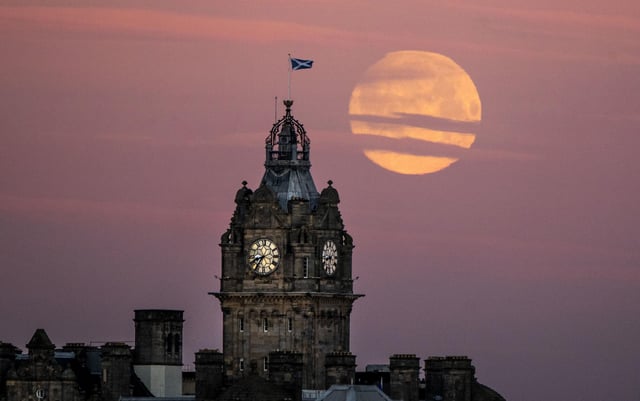 The moon sets behind the Balmoral Clock in Edinburgh. Photo: Jane Barlow/PA Wire.