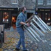 A man stacking away chairs outside The last Drop pub in The Grassmarket, Edinburgh.