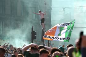 A Celtic fan perches on a set of traffic lights as supporters gathered at Glasgow Cross on Saturday to celebrate winning the Premiership (Picture: Andrew Milligan/PA Wire)