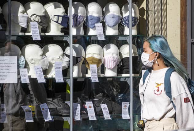 A woman wearing a protective face mask walks past a shop selling masks in Edinburgh city centre. Jane Barlow/PA Wire