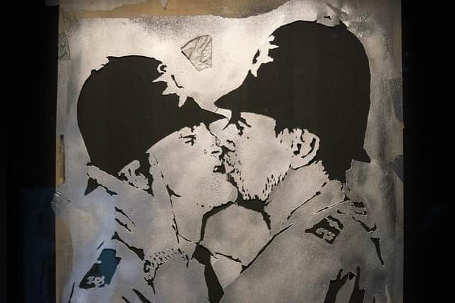 Stencil featuring kissing policemen in the new show by artist Banksy.