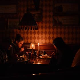 This photograph, taken in October 2022, shows visitors eating lunch by candlelight due to a power cut at a bar in the centre of the Ukrainian capital of Kyiv. Picture: Sergei Supinsky/AFP via Getty Images