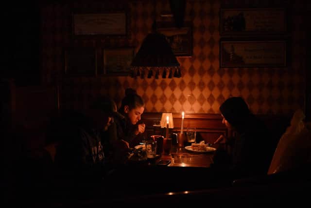 This photograph, taken in October 2022, shows visitors eating lunch by candlelight due to a power cut at a bar in the centre of the Ukrainian capital of Kyiv. Picture: Sergei Supinsky/AFP via Getty Images