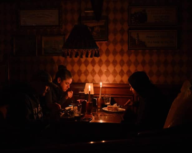 This photograph, taken in October 2022, shows visitors eating lunch by candlelight due to a power cut at a bar in the centre of the Ukrainian capital of Kyiv. Picture: Sergei Supinsky/AFP via Getty Images