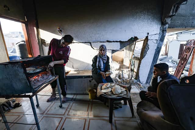 Family members prepare traditional unleavened bread in their destroyed house in Rafah in the southern Gaza Strip. The World Health Organisation has warned 93 per cent of the population have hit a crisis level of hunger.