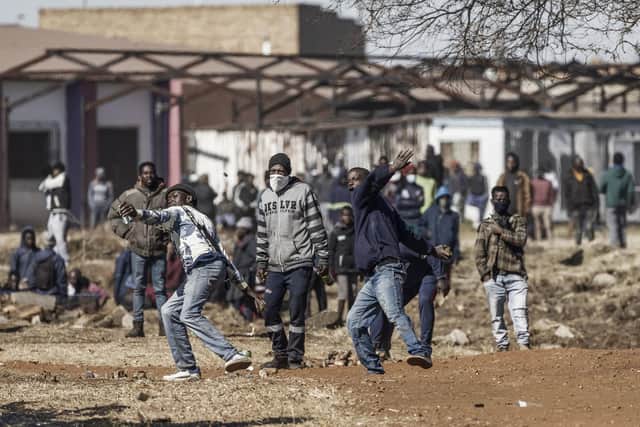 Disgruntled residents throw rocks as they confront police officers at the entrance of a partially looted mall in Vosloorus in Gauteng province. Picture: Marco Longari/AFP via Getty Images