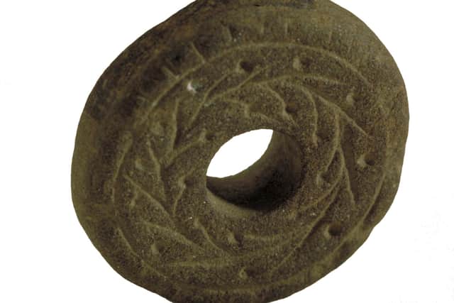 A 15th Century spindle whorl decorated with a feather design which was used as a healing charm which was used to ward off spirits as well as cast curses. PIC: Aberdeen University.