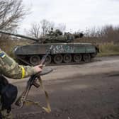 A Ukrainian soldier walks past a destroyed tank near Borivske, Kharkiv region .