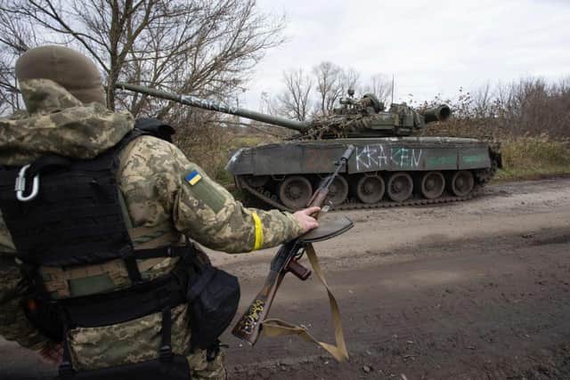 A Ukrainian soldier walks past a destroyed tank near Borivske, Kharkiv region .