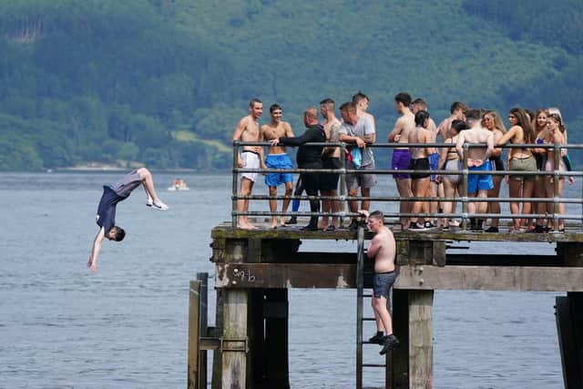 People jump from a pier into the water of Loch Lomond, in the village of Luss in Argyll and Bute, earlier this summer. Picture: PA