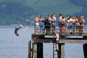 People jump from a pier into the water of Loch Lomond, in the village of Luss in Argyll and Bute, earlier this summer. Picture: PA