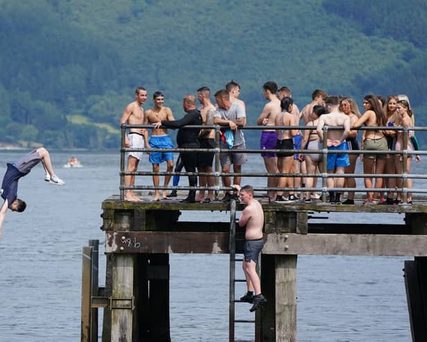 People jump from a pier into the water of Loch Lomond, in the village of Luss in Argyll and Bute, earlier this summer. Picture: PA
