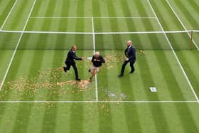 A protester is challenged by security on court 18 after a Just Stop Oil protest using orange confetti and a jigsaw puzzle during the Women's Singles first round match between Katie Boulter of Great Britain and Daria Saville of Australia.