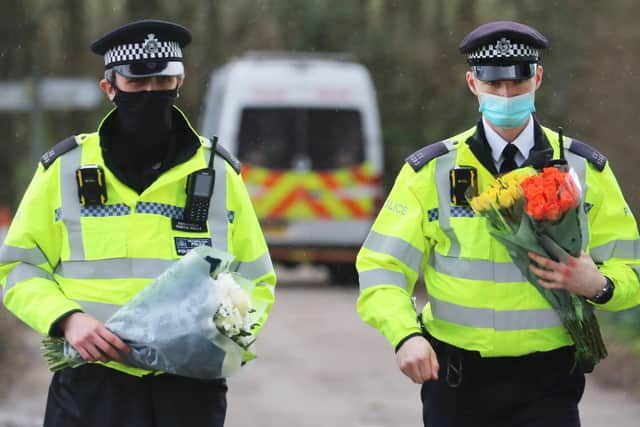 Police officers carry flowers left by members of the public close to the place where human remains were found near Ashford in Kent (Picture: Gareth Fuller/PA Wire)