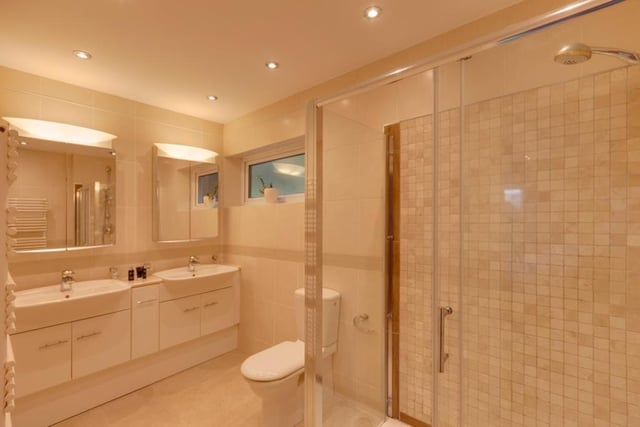 The master bedroom's ensuite contains two hand basins, with storage below and mirrored cabinets above, a fitted shower in a corner enclosure and a wc.