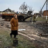 A woman walks past a destroyed armoured personal carrier in the liberated village of Petropavlivka near Kupiansk, Kharkiv region on December 15, 2022, amid the Russian invasion of Ukraine. (Photo by SERGEY BOBOK / AFP) (Photo by SERGEY BOBOK/AFP via Getty Images)