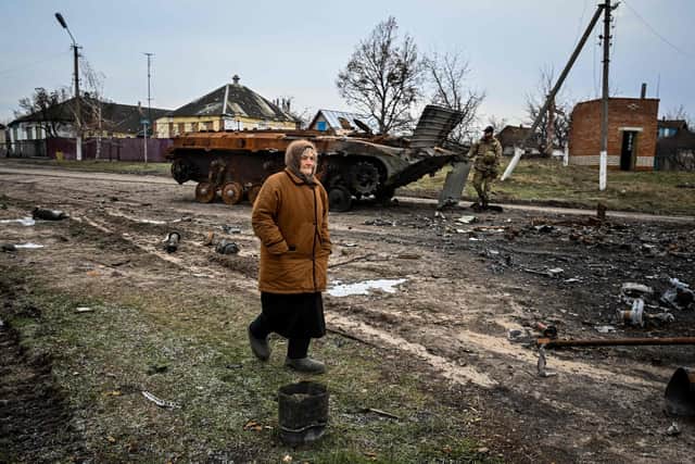A woman walks past a destroyed armoured personal carrier in the liberated village of Petropavlivka near Kupiansk, Kharkiv region on December 15, 2022, amid the Russian invasion of Ukraine. (Photo by SERGEY BOBOK / AFP) (Photo by SERGEY BOBOK/AFP via Getty Images)