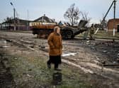 A woman walks past a destroyed armoured personal carrier in the liberated village of Petropavlivka near Kupiansk, Kharkiv region on December 15, 2022, amid the Russian invasion of Ukraine. (Photo by SERGEY BOBOK / AFP) (Photo by SERGEY BOBOK/AFP via Getty Images)