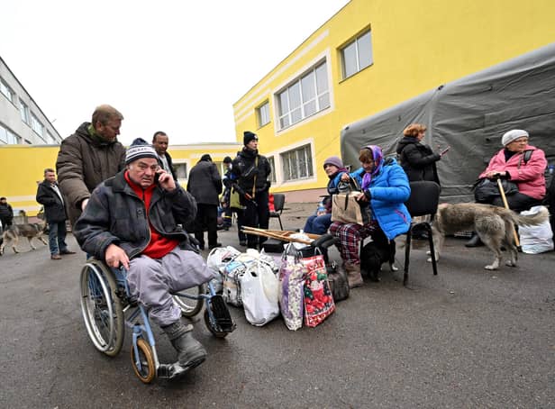A rescuer assists a disabled man after he was evacuated from the city of Irpin to the outskirts of Ukrainian capital Kyiv last month