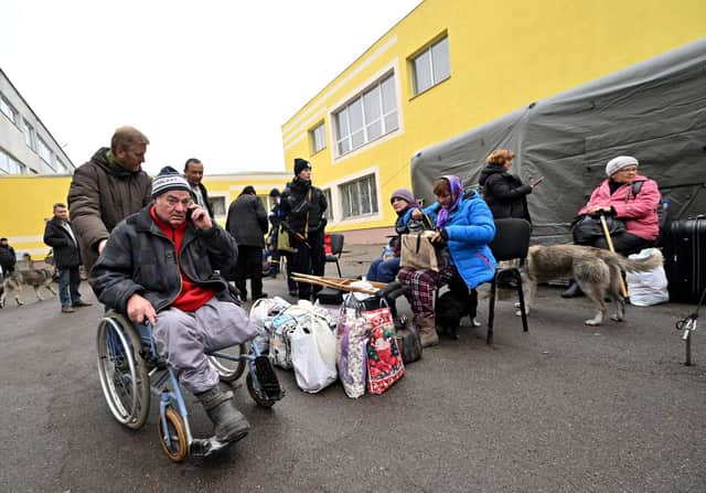 A rescuer assists a disabled man after he was evacuated from the city of Irpin to the outskirts of Ukrainian capital Kyiv last month