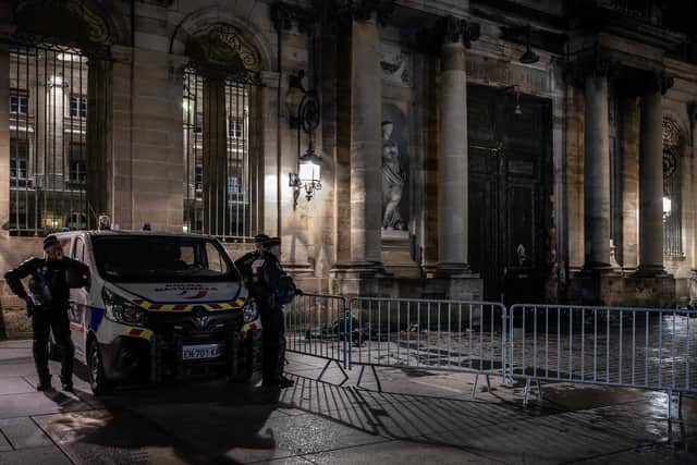Police officers stand guard next to the gate of the city hall after it was set on fire by protesters after a demonstration in Bordeaux. (Photo by PHILIPPE LOPEZ/AFP via Getty Images)