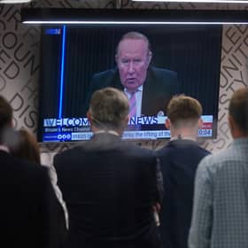 Staff in the green room watching a television screen showing presenter Andrew Neil broadcast from a studio, during the launch event for new TV channel GB News.