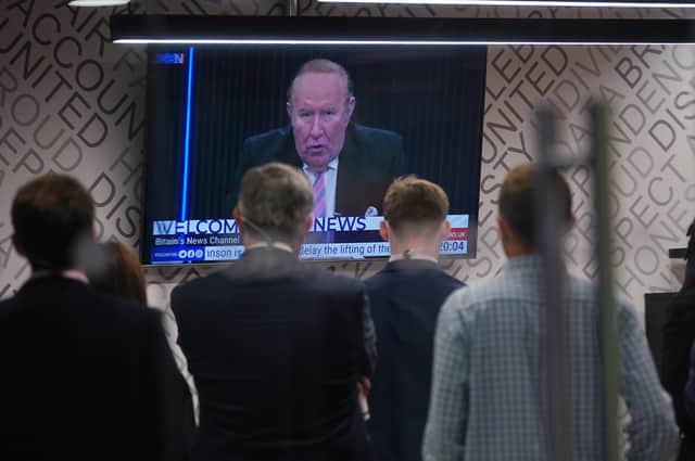 Staff in the green room watching a television screen showing presenter Andrew Neil broadcast from a studio, during the launch event for new TV channel GB News.