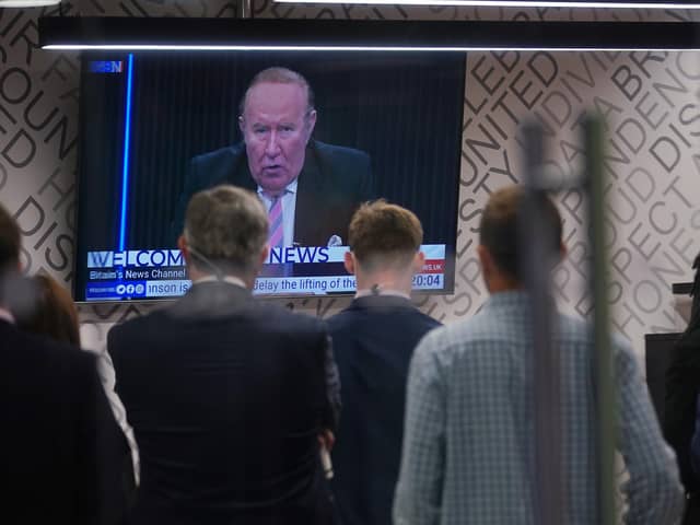 Staff in the green room watching a television screen showing presenter Andrew Neil broadcast from a studio, during the launch event for new TV channel GB News.