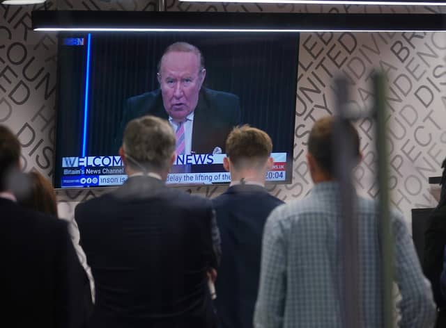 Staff in the green room watching a television screen showing presenter Andrew Neil broadcast from a studio, during the launch event for new TV channel GB News.
