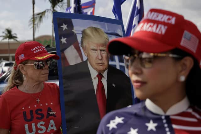 Supporters of former U.S. President Donald Trump await the motorcade transporting the former US president to Palm Beach International Airport. He is due to appear at a  Manhattan courthouse on Tuesday following his indictment by a grand jury. (Photo by Alon Skuy/Getty Images)