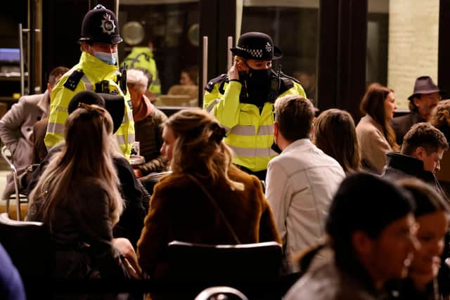 Police officers speak with customers enjoying drinks at tables outside the pubs and bars in London's Soho after the relaxation of lockdown restrictions earlier this month in England (Picture: Tolga Akmen/AFP via Getty Images)