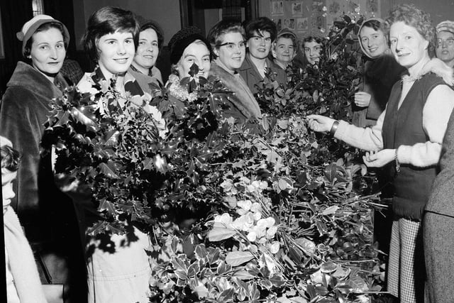 Mrs M Stevens helps customers choose their perfect festive decoration at the Davidsons Mains Church 'Holly Morning' in Edinburgh in 1962.