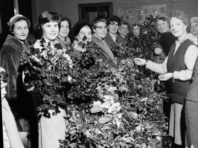 Mrs M Stevens helps customers choose their perfect festive decoration at the Davidsons Mains Church 'Holly Morning' in Edinburgh in 1962.
