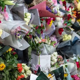 A young boy lays flowers outside Buckingham Palace