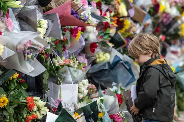 A young boy lays flowers outside Buckingham Palace