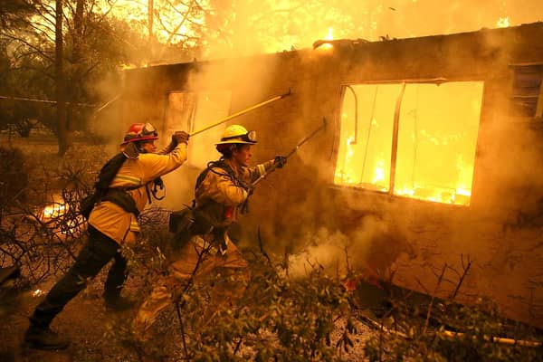 Firefighters try to keep flames from burning home from spreading to a neighboring apartment complex as they battle the Camp Fire in 2018 in Paradise, California (Picture: Justin Sullivan/Getty Images)