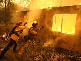 Firefighters try to keep flames from burning home from spreading to a neighboring apartment complex as they battle the Camp Fire in 2018 in Paradise, California (Picture: Justin Sullivan/Getty Images)