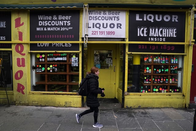 A member of the public walks through the set in Glasgow, for what is believed to be the film set of the new Batgirl movie as a liquor stores shows a half bottle of Buckfast going for $34.99 (Photo: Andrew Milligan, PA).