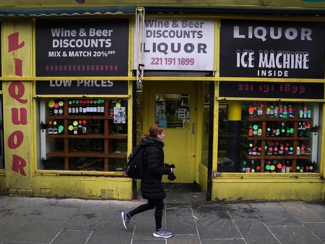 A member of the public walks through the set in Glasgow, for what is believed to be the film set of the new Batgirl movie as a liquor stores shows a half bottle of Buckfast going for $34.99 (Photo: Andrew Milligan, PA).